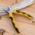 Deli Tools EDL2007 combination pliers, 7 inch, yellow and black, in use