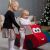 Lányok játszanak az IGLU Soft Play Autós Játék piros autó hintával a karácsonyfa mellett