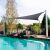 Gray triangle shade sail over a swimming pool.