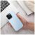 Kézben tartott világoskék Simply Roar Cloud Skin iPhone 12 tok, laptop a háttérben.