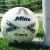 Mitre Ultimatch Evo FIFA 4-es méretű focilabda füvön a kapufa mellett, játékra készen