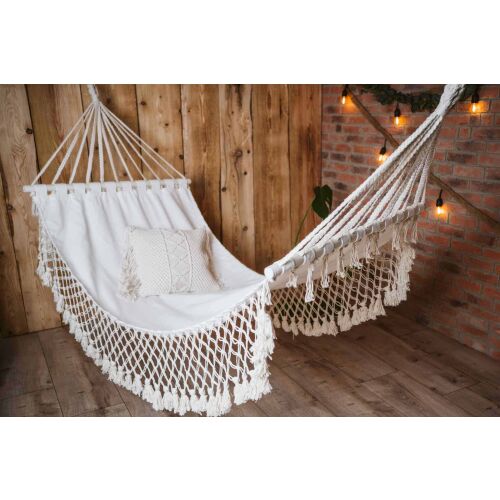 Boho WOOD függőágy, stílusos fehér pamut függőágy makramé részletekkel és fa rudakkal, beltéren, rusztikus fa és téglafal előtt elhelyezve, bohém és hívogató hangulatot teremtve finom világítással - Függőágy