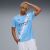 Fiatal férfi viseli a Puma MCFC HOME JERSEY REPLICA férfi világoskék focimezt, bemutatva az elülső dizájnt szponzorlogókkal és klubcímerrel