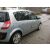 Ezüst színű Renault SCENIC II hátsó háromnegyedes nézete króm oldalsó ajtóburkolatokkal, macskaköves utcán parkolva.