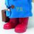 Közelkép Paddington mackó piros csizmájáról és a kék kabáton hímzett 'P.B.' monogramról