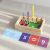 Montessori fa oktató puzzle válogató kémcsövekkel, tele színes golyókkal és matematikai kártyákkal (számok és műveleti jelek) elrendezve előtte, bemutatva a számolást és a logikát.