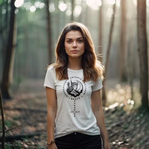 Artemis - Női póló / Fehér. Egy nő visel egy fehér pólót fekete kör alakú grafikával, amelyen Artemis és a szöveg látható: 'INDEPENDENT ARTEMIS AUTONOMOUS BRAVE OWN SPIRIT'. A póló karcsúsított fazonú, és a nő egy erdei környezetben áll a szabadban. - Női póló