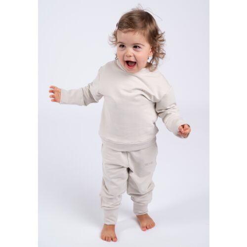 Boldog tipegő Moniel Basic Light Beige gyerek melegítőben, teljes alakos kép, játékos póz - Baba és gyerek divat