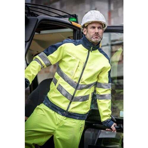 Férfi Regatta RETRA625 HI-VIS PRO 3 rétegű softshell kabátban és nadrágban, sisakkal, építőipari járműben, bemutatva a biztonsági munkaruházatot - Munkavédelem
