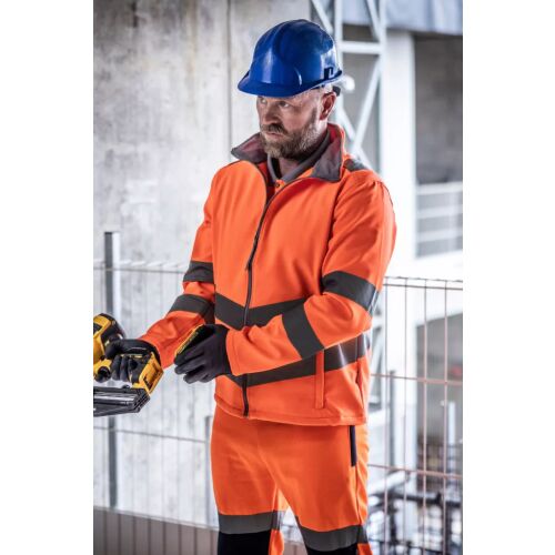 Férfi narancssárga Regatta HI-VIS PRO CONTRACT ABLAZE kétrétegű softshell dzsekiben, fényvisszaverő csíkokkal és kék védősisakkal, kültéri építkezésen dolgozik - Építkezés és felújítás