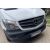 Dinamikus ferde felvétel egy fehér Mercedes Sprinter W906-ról, újonnan beépített króm hűtőrács csíkokkal, modern és elegáns frissítést bemutatva.