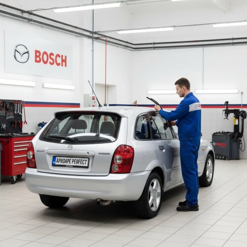 Szerelő szerel fel egy Bosch Twin H341 hátsó ablaktörlőt egy ezüst Mazda 323 F VI-ra egy szervizben - ‪Ablaktörlő lapát