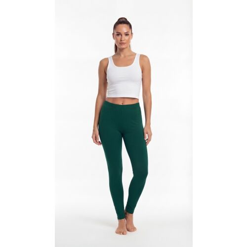 Teljes alakos kép egy nőről, aki sötétzöld pamut leggingset és fehér crop topot visel, fehér háttér előtt pózolva, bemutatva a leggings illeszkedését és színét. - Női leggings