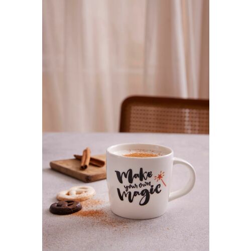 Hermia Mug Fehér porcelán kávéscsésze "Make your own magic" felirattal, forró itallal megtöltve, kekszek és fahéjrudak mellett egy fa deszkán. - Hermia