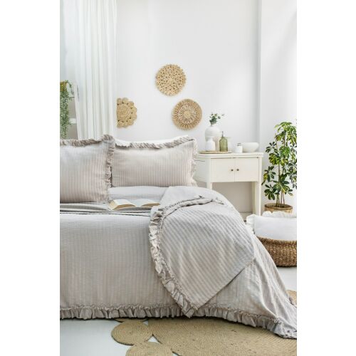 L'essential Maison dupla pique szett bézs Martha, teljes képet mutat a bézs fodros pique ágytakaróról és két hozzáillő fodros párnahuzatról egy ágyon egy világos hálószobában, kiemelve az elegáns esést és textórát 