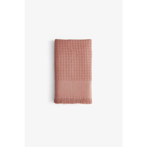 L'essential Maison Anika lazac kéztörlő 100% pamut és Tencel keverékből, waffle mintával és rojtokkal, összehajtva, fehér alapon - Dekoráció