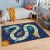 Conceptum Hypnose Carpet 100x180 Multicolor Hmı Kdc-20, élénk űrtémájú játszószőnyeg játéktáblával, rakétával és űrhajóssal egy gyerekszoba berendezésben, ággyal és éjjeli asztallal