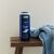 NIVEA MEN Protect & Care 3in1 tusfürdő, 500 ml, fa sámlin kék törölközővel, fürdőszobai környezetben