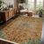 Conceptum Hypnose Carpet (200 x 300) Multicolor 324 egy hangulatos szobában, fa bútorokkal, ablakkal és növényekkel, bemutatva a szőnyeg élénk, kopott mintázatát és azt, hogyan egészíti ki a rusztikus dekorációt
