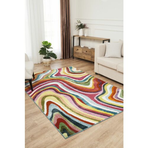 Conceptum Hypnose szőnyeg (140 x 200) Multicolor Picasso egy modern nappaliban, vibráló absztrakt mintázatával és puha textúrájával fa padlón, bézs kanapéval és növénnyel. - Szőnyeg
