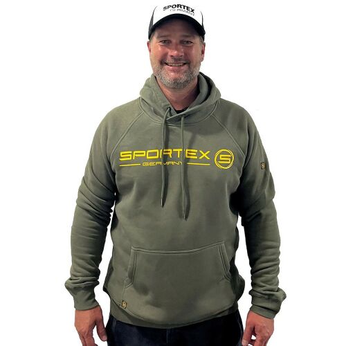 SPORTEX HOODIE OLIVE GREEN M, elölnézet egy férfiról, aki olíva zöld SPORTEX pulóvert visel sárga logóval, fehér háttérrel, horgászathoz és kültéri tevékenységekhez alkalmas - Munkás pulóver