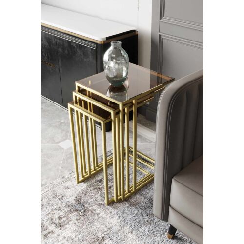 Hanah Home Nesting Table (3 darab) Arany Bronz Mira, modern háromrészes egymásba tolható asztal szett arany fémvázzal és bronz üveglappal, nappali környezetben, részben látható kanapé és szekrény - Bútor