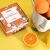 Ancient Wisdom C-vitaminos Fürdőbomba Készlet, narancssárga csomagolás citrus illusztrációval és friss narancsszeletekkel sárga háttéren, bemutatva az ajándékdobozt és a fürdőbombákat