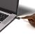 Egy YUBICO YubiKey 5 NFC biztonsági kulcs egy laptop USB portjába dugva, egy ujjal érintve az arany aktiváló kört