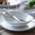 DUKA TIME fehér porcelán ovális tányér és tál evőeszközökkel, kiemelve az étkészlet modern designját és sima felületét