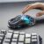 GravaStar Mercury M2 Transparent Black vezeték nélküli gamer egér használat közben, kézzel nyúlva utána, bemutatva kényelmes illeszkedését és elegáns designját