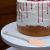 Bewello szilikon spatula világosrózsaszín fejjel és szürke nyéllel egy tortaállványon egy részben díszített torta mellett, ideális sütéshez és krémek kenéséhez