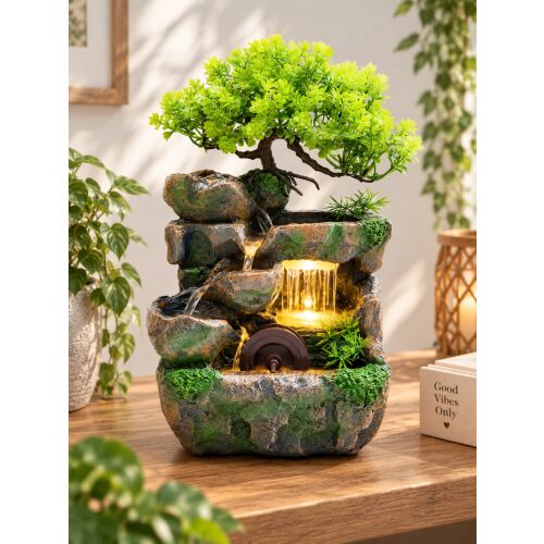 Bonsai vízesés szökőkút LED világítással és vízikerékkel, nyugodt beltéri hangulatot teremtve egy fa asztalon, buja zöld növényekkel. - Lakberendezés