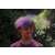 Man covered in holi powder with a cloud of purple and green powder above his head