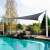 Grey triangular sun sail, 3.6x3.6x3.6m, providing shade for pool areas