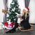 Woman with Christmas hat sitting near decorated Springos Christmas tree with gifts