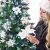 Woman decorating a Springos Christmas tree with white poinsettia ornaments