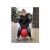 Child bouncing on a red Ugrólabda hopper ball with a funny face