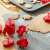 Red plastic cookie cutters with spring-loaded plungers, shown in use on a baking sheet and a silicone baking mat