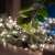 Somogyi Home Micro LED fairy lights, 50 warm white lights, on a table with green leaves