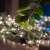 Somogyi Home Micro LED fairy lights, 50 warm white lights, on a table with green leaves