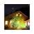 LED Christmas projector with disco ball effect, showing the projected light on a house and a Christmas tree