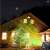 LED Christmas projector with disco ball effect, showing the projected light on a house and a Christmas tree