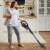 Woman using Tesla AeroStar T300 corded stick vacuum cleaner in a kitchen