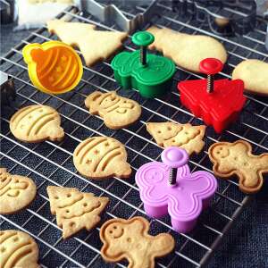 Set of 3 cookie cutters, including Christmas tree, snowman and gingerbread man shapes, with cookies made with them on a baking rack - Cookie cutter