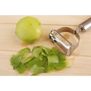 Stainless steel peeler with a green apple and its peelings on a wooden surface - Handheld slicer