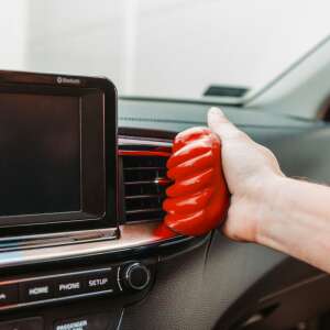 Mână care ține gelul universal de curățare M-N-C roșu, curăță grila de ventilație a mașinii - Produse de curățare pentru calculatoare