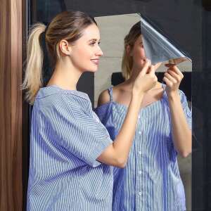 Nő kék tükör matricát ragaszt fel a falra - Lakberendezés