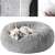 Grey plush dog bed with a dog sleeping in it, showing the soft fur and the raised edges