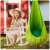 NeoSport single hanging swing, green, with cushion, child sitting on a rocking chair in the background