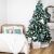 Christmas tree decorated with light blue ornaments in bedroom setting